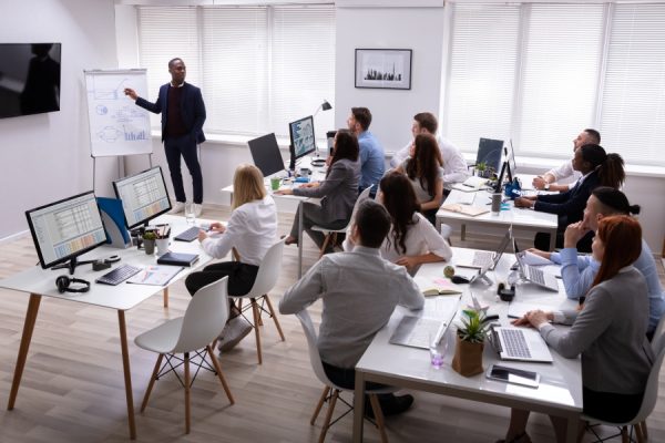 A teacher presenting in front of a room of individuals